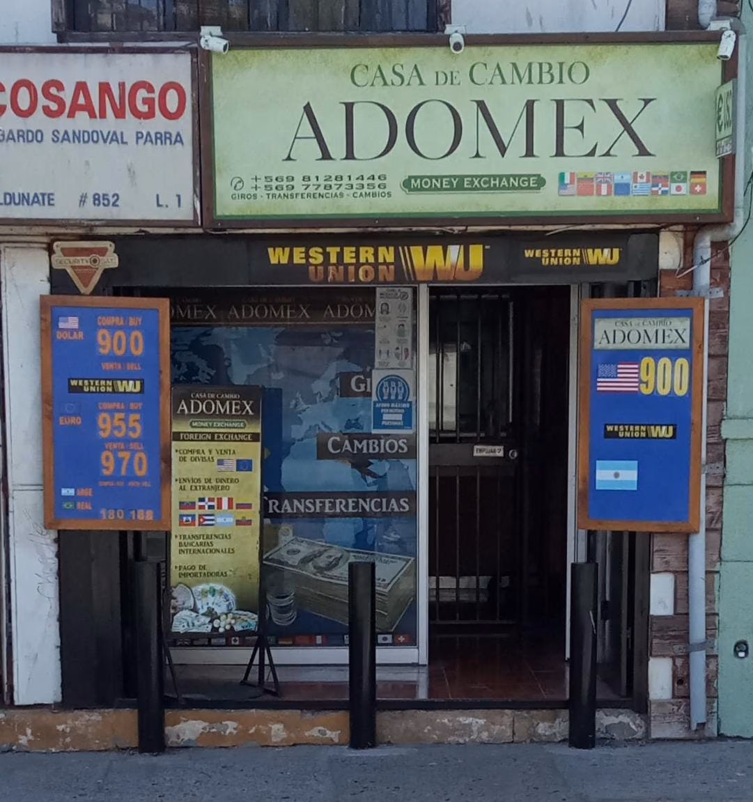 Fachada de Casa de Cambio Adomex en José Santiago Aldunate 852: letrero verde, cartel de Western Union, puerta con reja y una pizarra azul de compra y venta a cada lado.